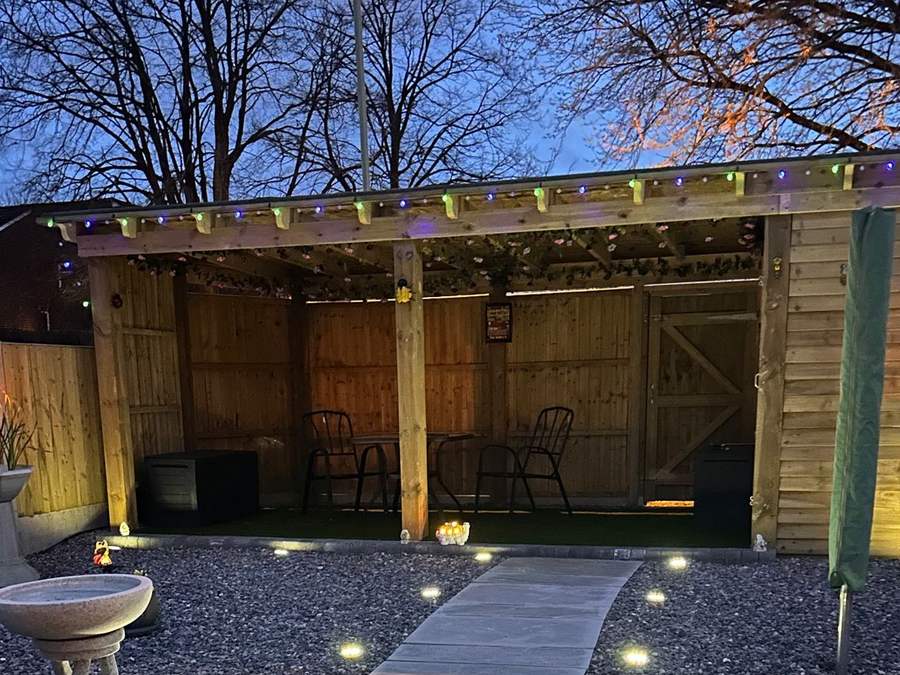Timber pergola with festoon lights over a seating area at dusk