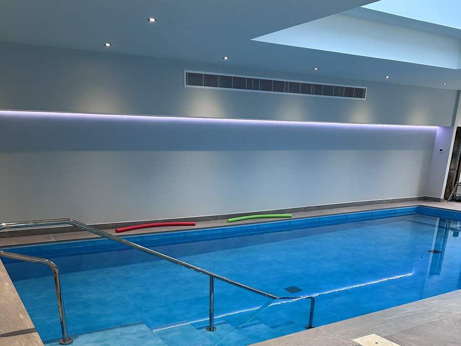Indoor swimming pool with stainless steel steps and a porcelain surround