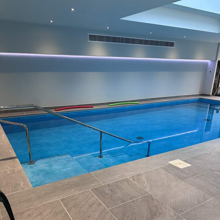 Indoor swimming pool with porcelain surround and stainless steel steps