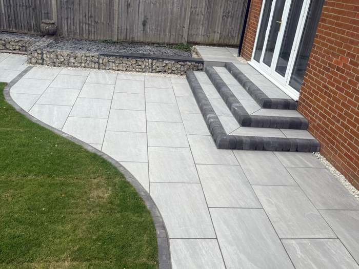 Grey porcelain patio and steps with a curved lawn edge