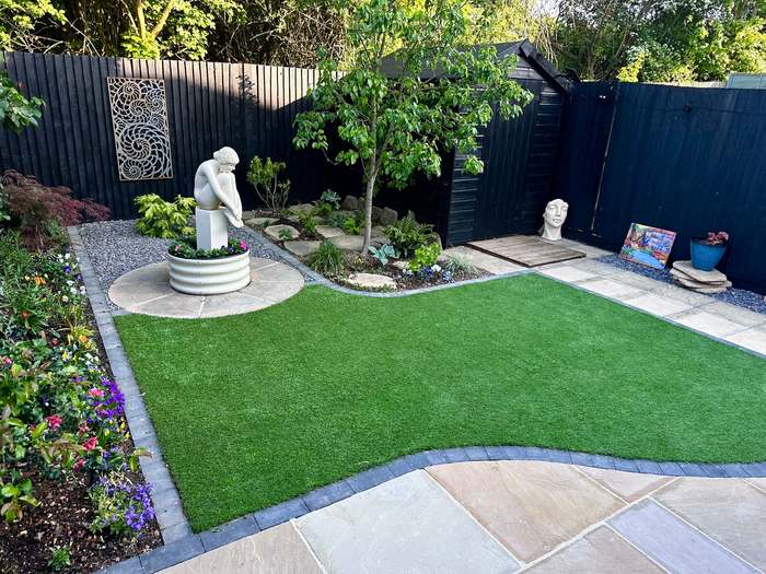 Artificial lawn, sandstone paving and statue in a landscaped garden