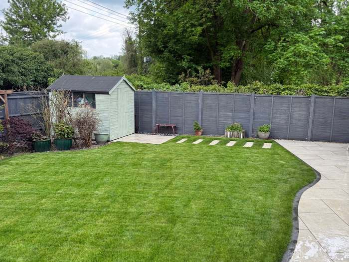 New lawn with stepping stones beside a wet porcelain patio