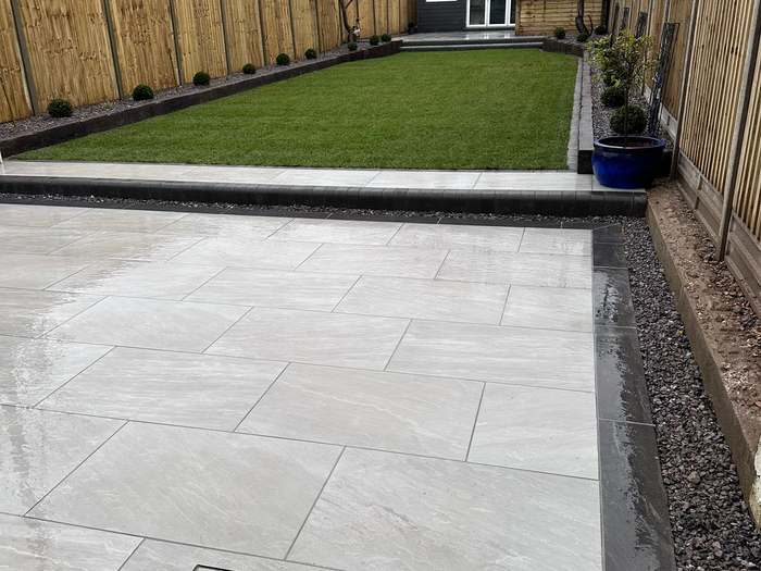 Grey porcelain patio with a recessed inspection cover in a fenced garden