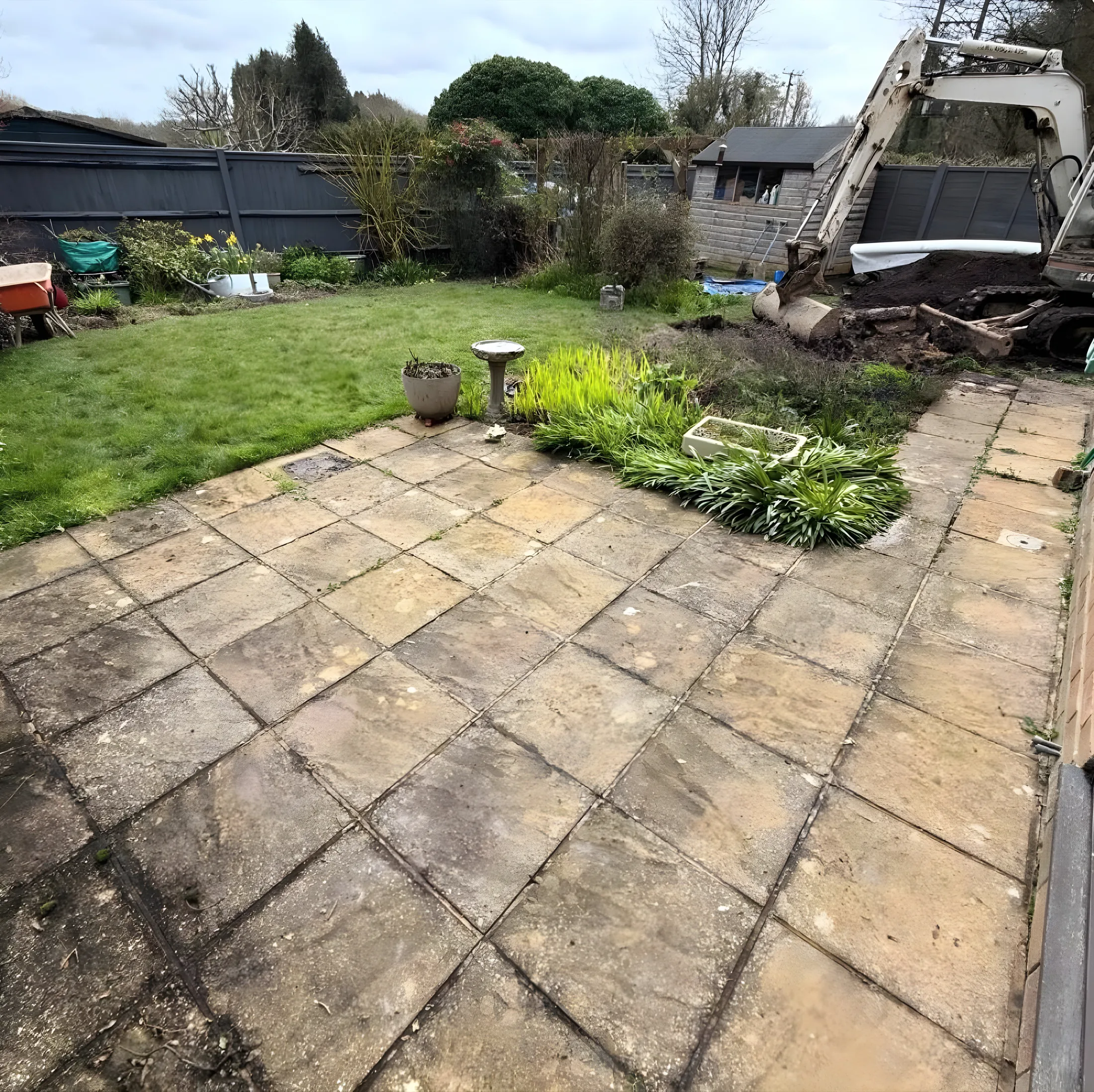 Garden before the work: worn patio and uneven lawn