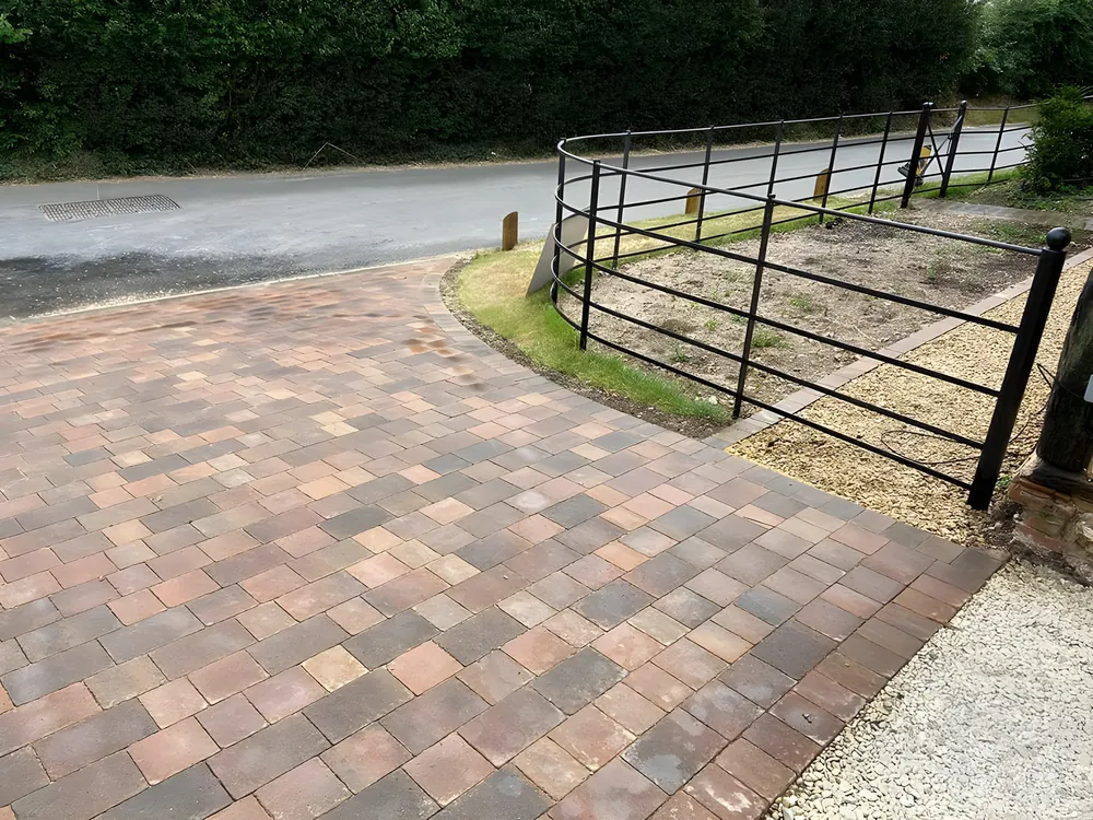 Multi tone block paved driveway curving past an iron field gate