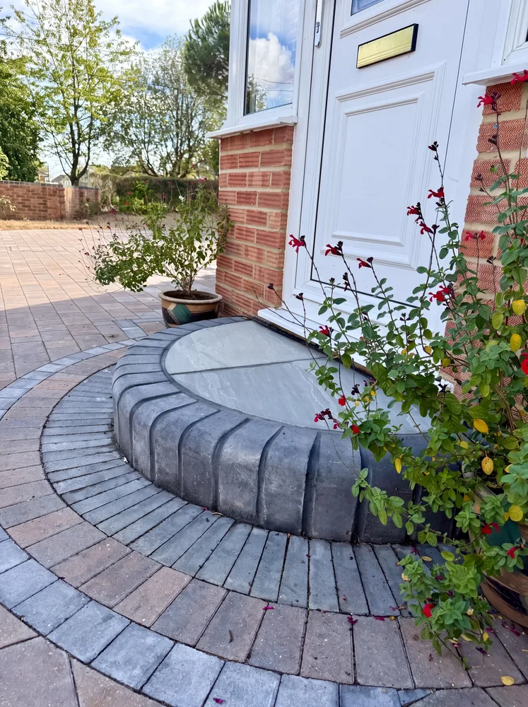 Curved bullnose front step and circular block paving at a white front door
