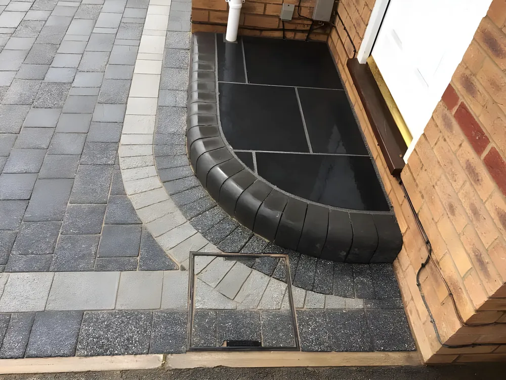 Curved bullnose step in dark paving with a block border