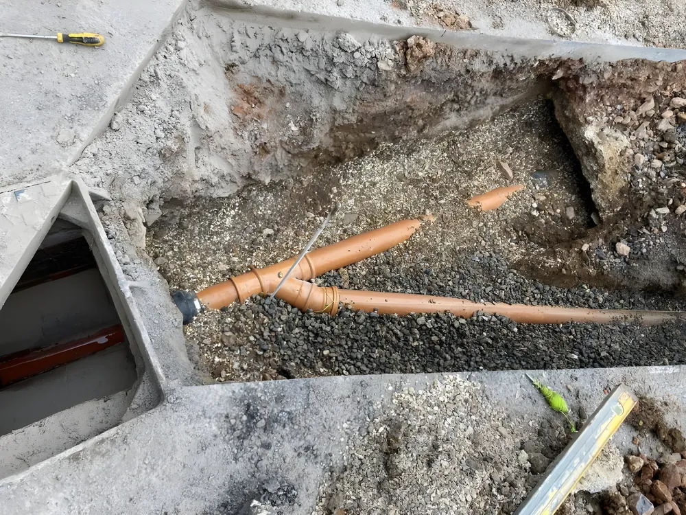 New drainage pipes bedded in gravel in an open trench