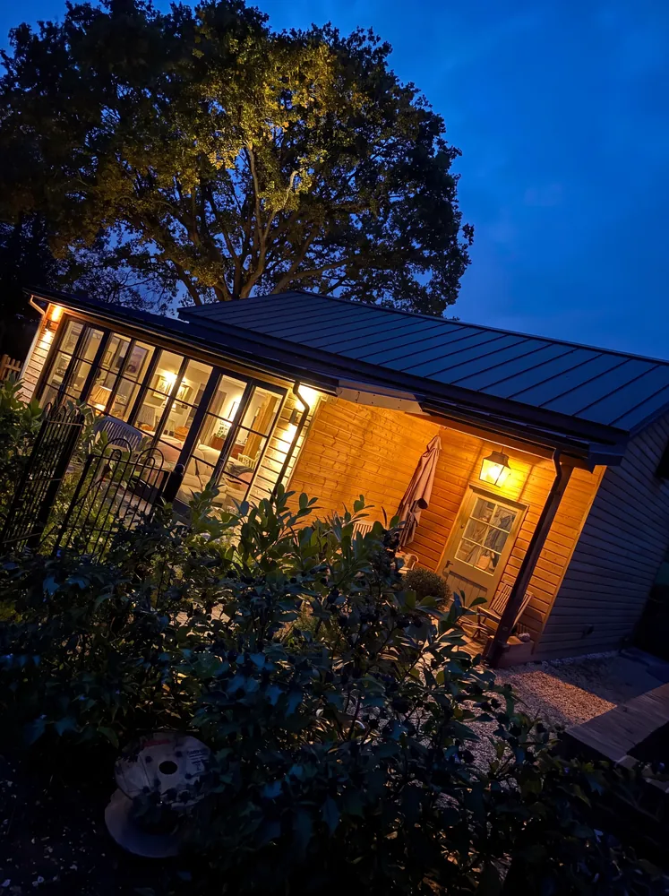 Timber garden room with glazed doors and a lantern lit porch at dusk
