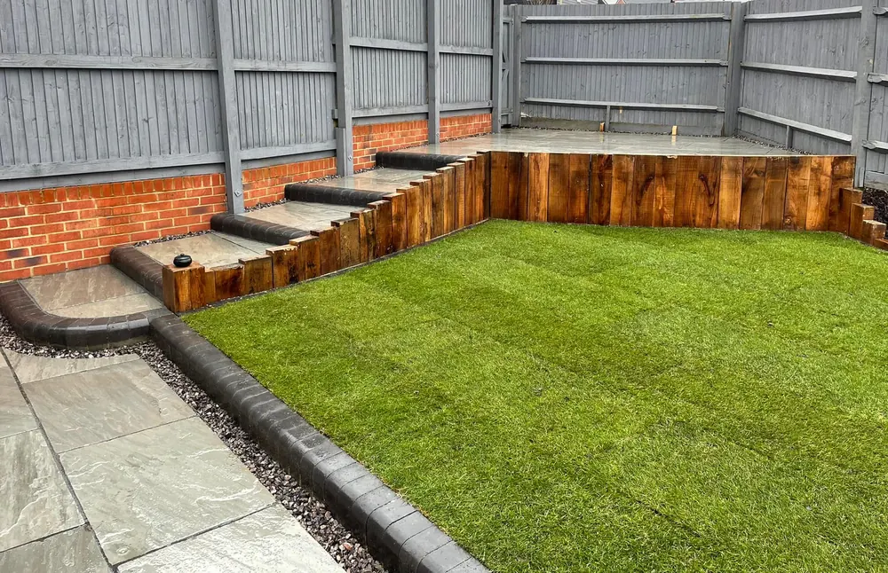Sleeper steps leading up to a new lawn with porcelain paving below