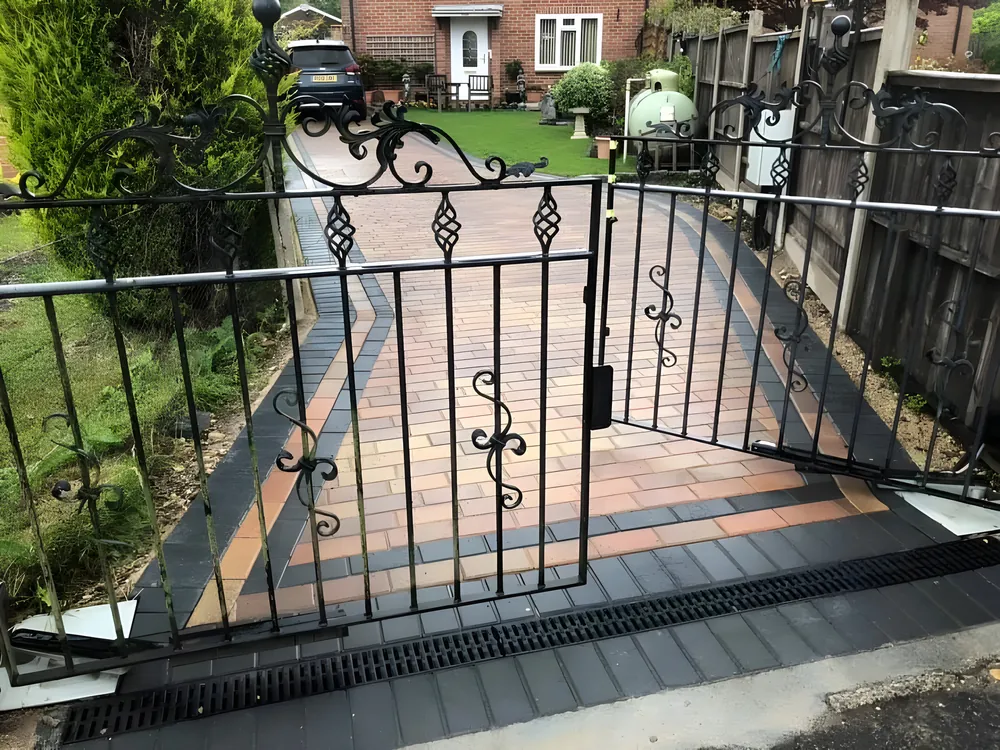 Iron gates opening onto a brindle block paved path with a charcoal border