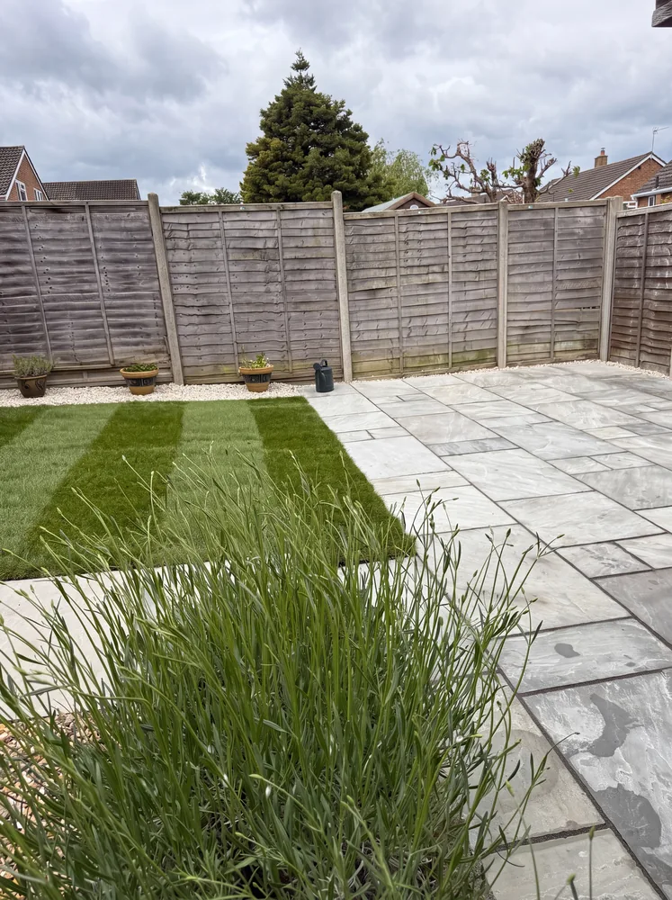 New striped lawn beside a light grey porcelain patio inside timber fencing