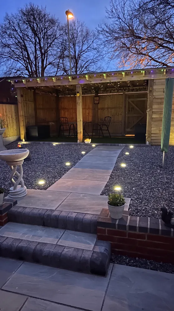 Lit pergola and paved seating area at night