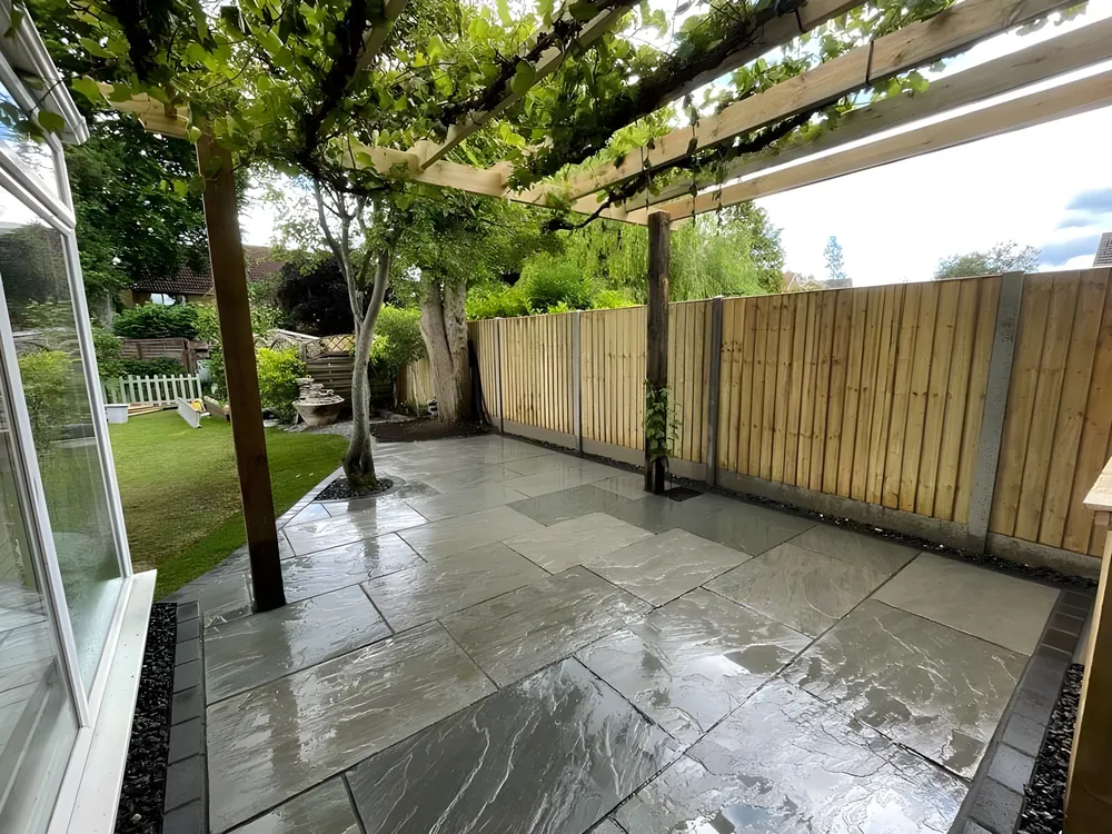Timber pergola over a porcelain patio beside a conservatory
