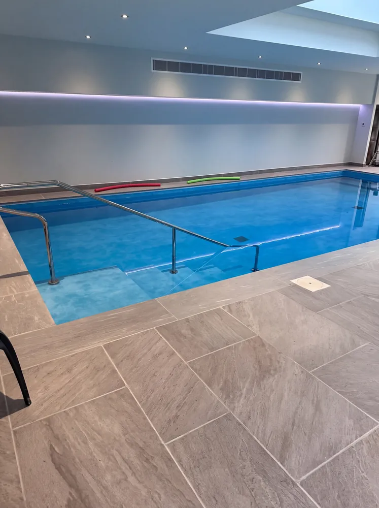 Indoor pool with porcelain paving, a handrail and steps