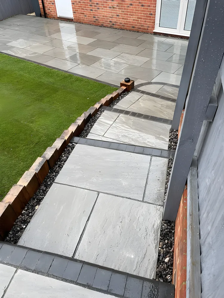 Porcelain side path with a brick edge between a lawn and the house