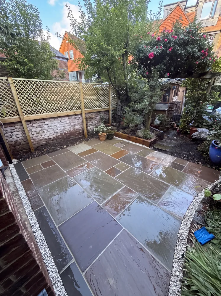 Sandstone patio with white gravel edging in a courtyard garden with a lattice topped wall