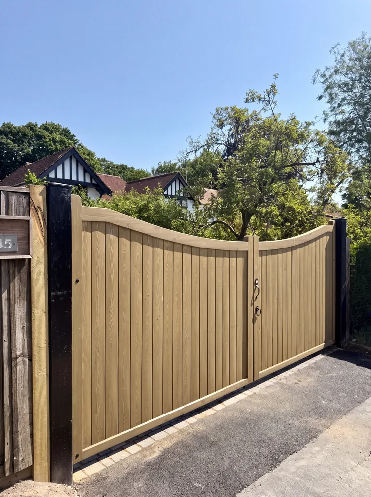 Pair of tall close boarded timber driveway gates above a tarmac drive