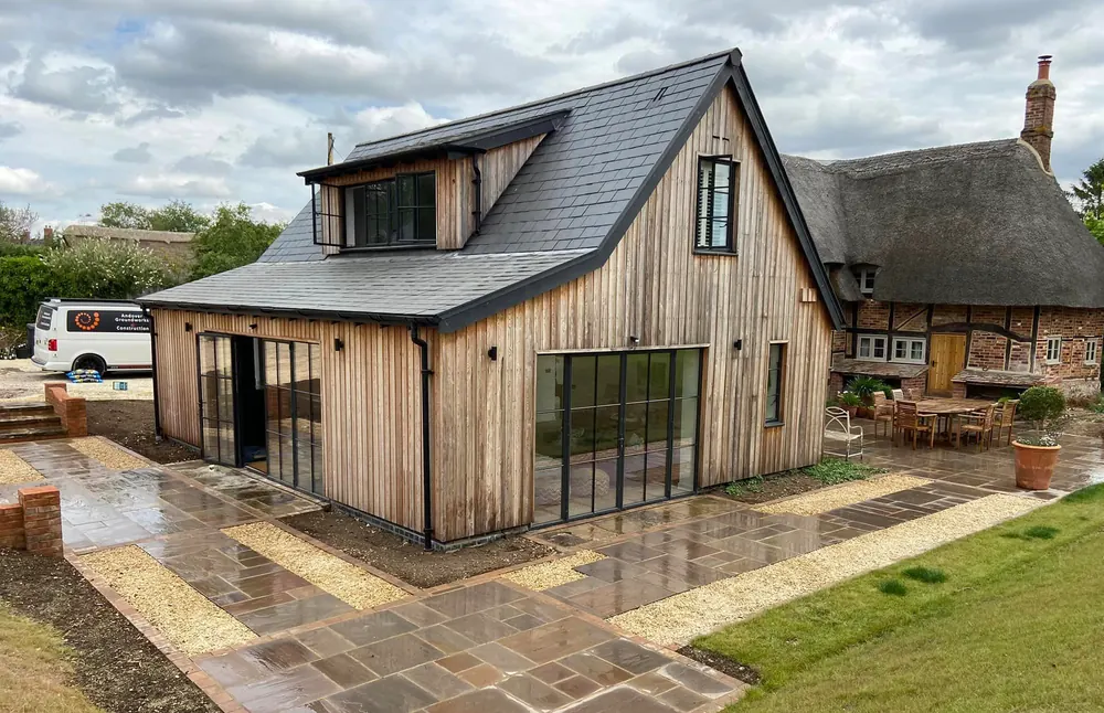 Timber clad new home with a sandstone patio and lawn