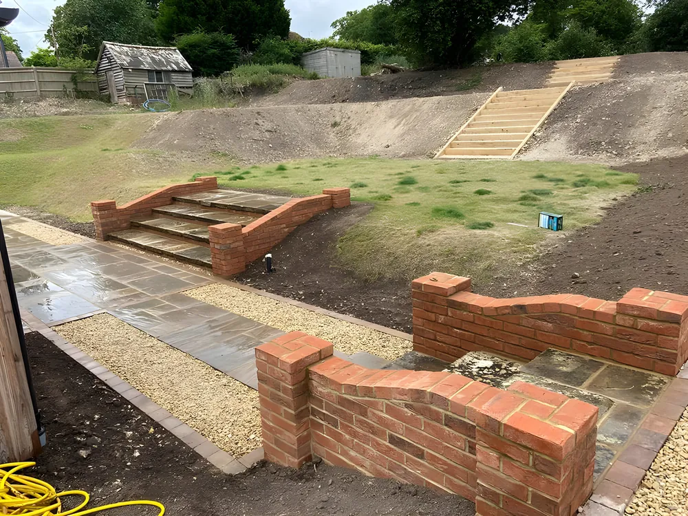 Brick retaining walls and steps being built into a sloping garden